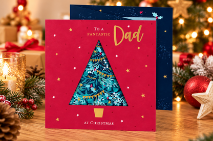 Fantastic Dad Christmas card with red cover and Christmas tree displayed beside festive decorations and candlelight