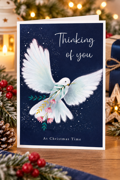White dove Thinking of You Christmas card displayed with festive candles and decorations