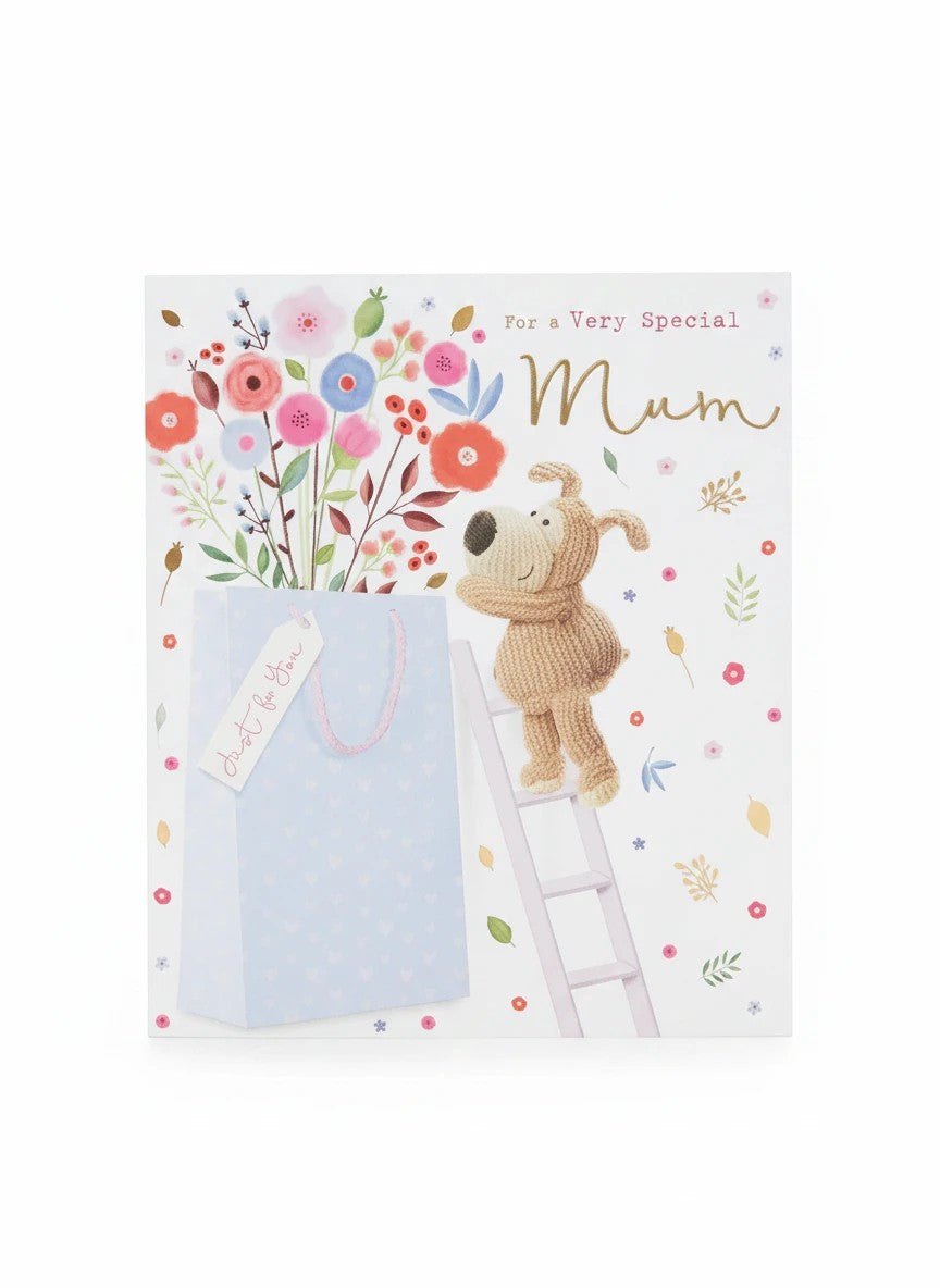 Made To Be Treasured Boofle birthday card for Mum, featuring a knitted dog on a ladder reaching for flowers, with a gift bag and gold foil details.